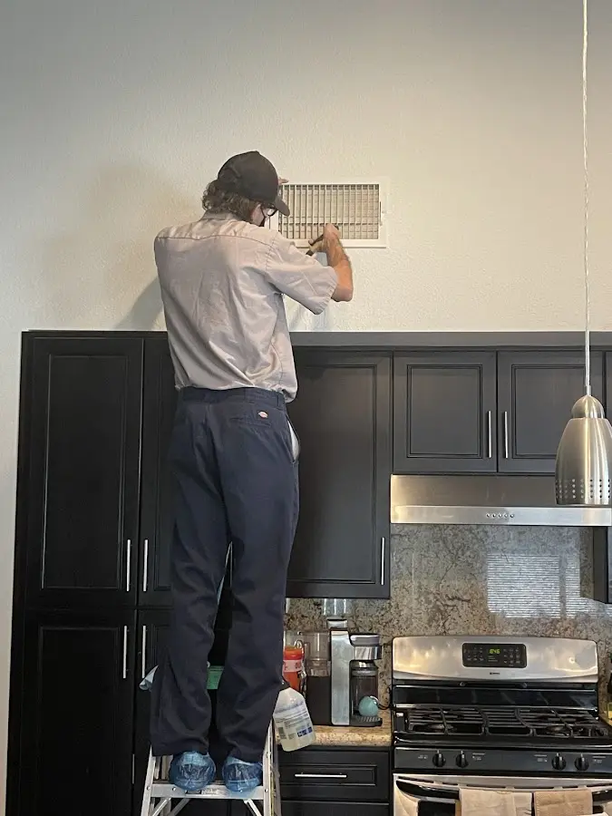 Technician inspecting an air vent during HVAC service in Ensley